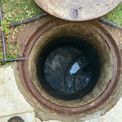 פתח ביוב פתוח עם מכסה מתכת מונח בצד