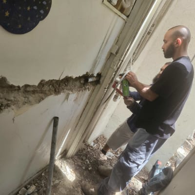 שני אנשים עובדים על צינור מים בקיר