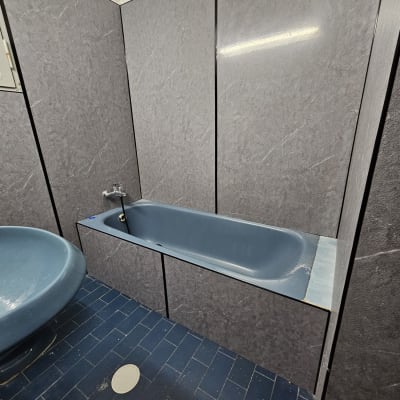 אמבטיה כחולה עם קירות אפורים ורצפת אריחים כחולה