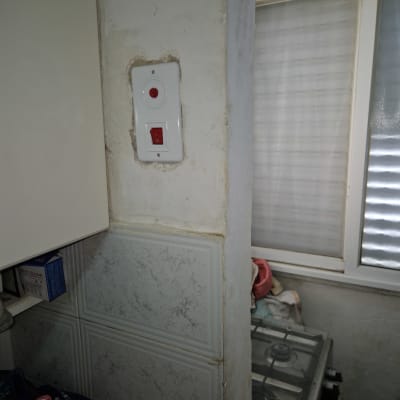 מתג חשמלי על קיר ליד חלון ותנור גז