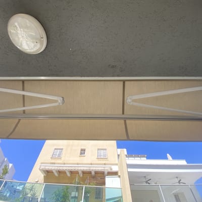 סוכך בד עם זרועות מתכת על קיר חיצוני