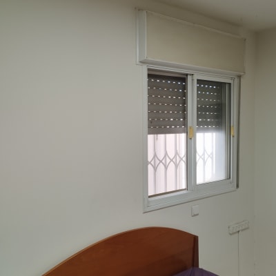 חלון עם תריסים סגורים חלקית בחדר שינה