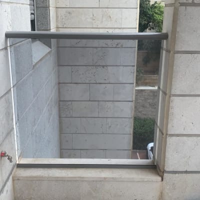 מעקה זכוכית בין קירות אבן במרפסת