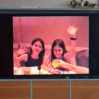 שתי ילדות יושבות ליד שולחן ומנפנפות בידיהן