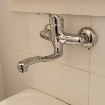 ברז כרום מותקן על קיר אריחים לבנים