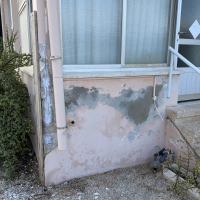 קיר חיצוני של בית עם קילופי צבע וטיח נפגע לפני שיפוץ ותיקון