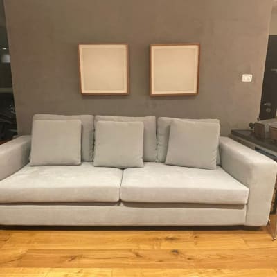 ספה אפורה עם כריות על רצפת עץ