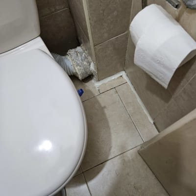 אסלה עם חיבורי צנרת ותיקון ריצוף