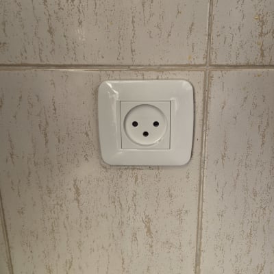 שקע חשמל לבן מותקן על קיר אריחים