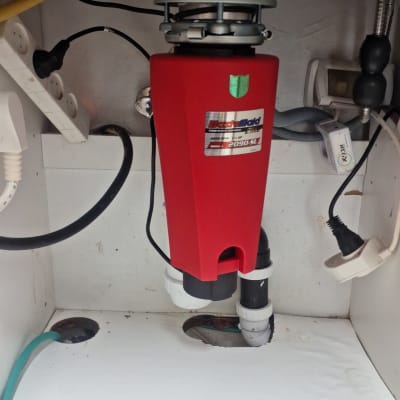 מתקן אדום מתחת לכיור עם צינורות וחיבורים