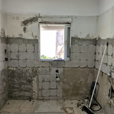 חדר בשיפוץ עם קירות חשופים וכלים על הרצפה