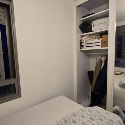 חדר שינה עם ארון פתוח ומיטה מסודרת