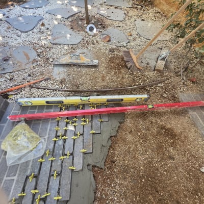 תהליך ריצוף חוץ בחצר עם אריחים, ספייסרים ופלס