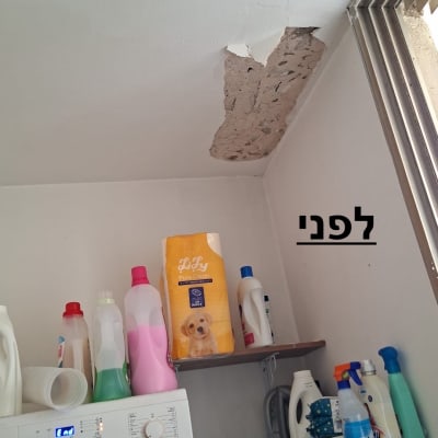 תקרה מתקלפת מעל מכונת כביסה ומדפים עם חומרי ניקוי