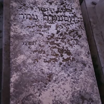 מצבה עם כיתוב בעברית ואבנים קטנות