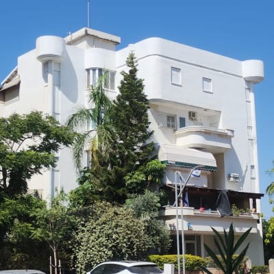 מנוף כתום ליד בניין לבן עם מרפסת