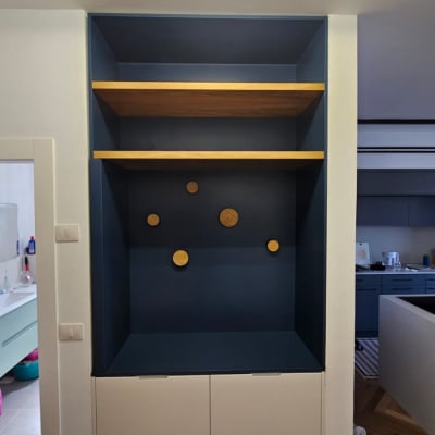 מדף עץ בתוך נישה כחולה עם עיגולים דקורטיביים