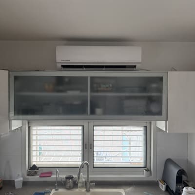 מזגן עילי אינוורטר מותקן על קיר במטבח לצד ארונות