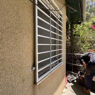 סורגי מתכת לבנים מותקנים על חלון קיר חיצוני