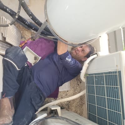 אדם מתקן דוד שמש עם כלים וצינורות