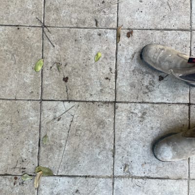 מגפי עבודה על רצפת אריחים מלוכלכת עם עלים יבשים