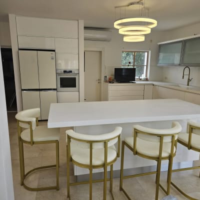 מטבח מודרני עם אי לבן וכיסאות בר