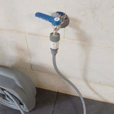 ברז עם ידית כחולה וצינור מחובר לקיר