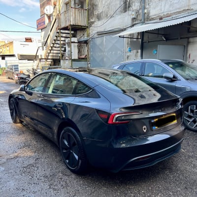 מכונית חשמלית שחורה חונה ליד בניין ישן