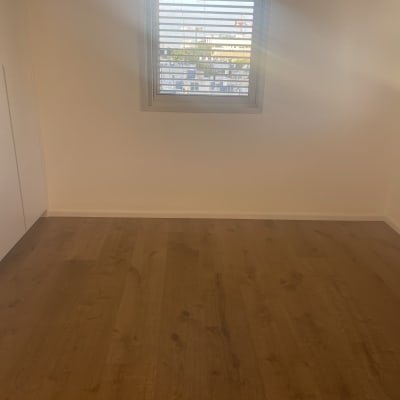 חדר עם רצפת עץ וחלון עם תריסים