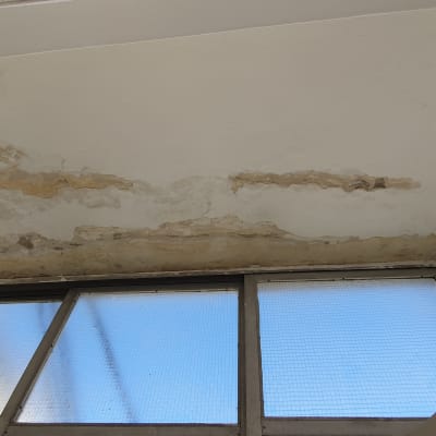 תקרה עם קילופי צבע מעל חלון זכוכית