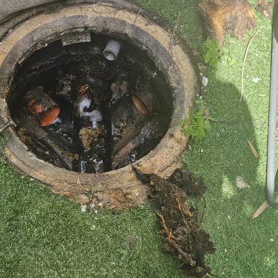 פתח ביוב עם מכסה פתוח וצינורות חשופים