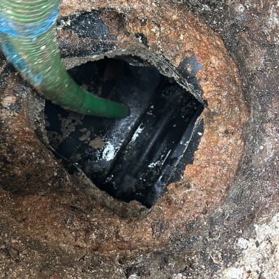 צינור ירוק שואב מתוך פתח ביוב חלוד