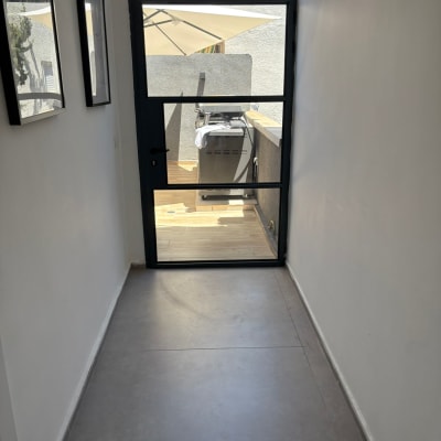 דלת זכוכית מובילה למרפסת עם גריל ושמשייה