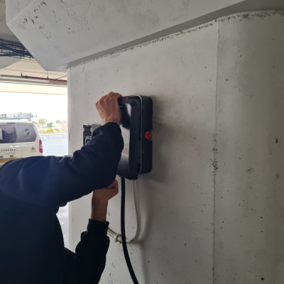 חשמלאי מתקין מטען חשמלי על קיר בטון