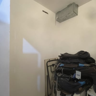 חדר עם קיר לבן וציוד מקופל בפינה