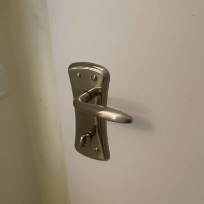 ידית דלת מתכתית על דלת לבנה