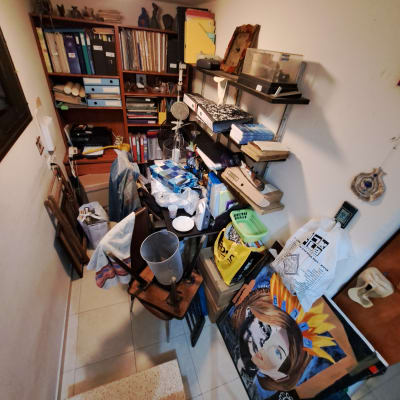 חדר עם מדפים עמוסים בספרים, קלסרים וציוד משרדי