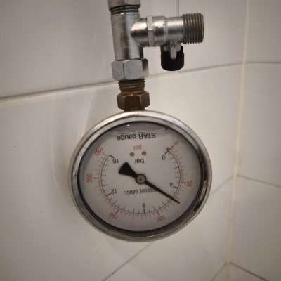 מד לחץ מים מותקן על קיר לבן