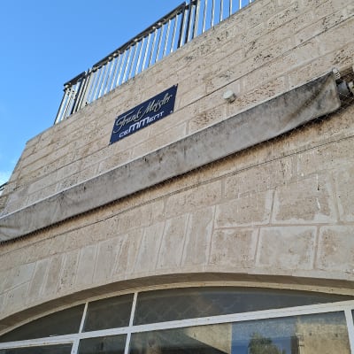 בניין עם שלט על קיר אבן וגדר מתכת