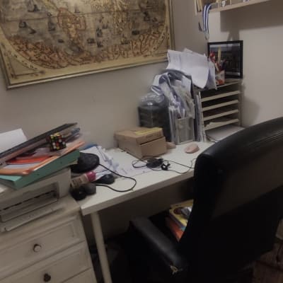 שולחן עבודה עם מסמכים, כיסא משרדי, מדפים עם גביעים