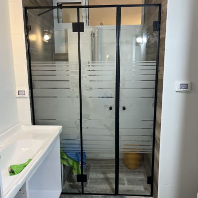 מקלחון זכוכית עם דלתות שחורות ומגבת צבעונית