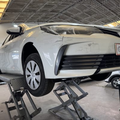 רכב לבן על מעלית במוסך עם שלט מוקד הרכב חיפה