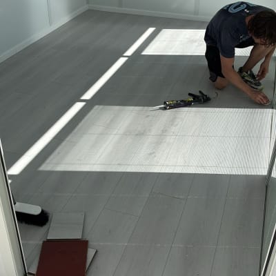 אדם מתקין פרקט בחדר עם רצפת עץ בהירה