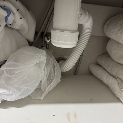 צינור פלסטיק לבן מתחת לכיור עם מגבות