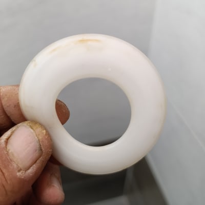 טבעת פלסטיק לבנה מוחזקת ביד מלוכלכת