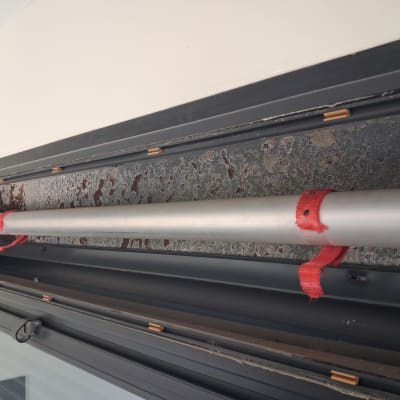 צינור מתכת עם רצועות אדומות בתוך מסגרת תריסים