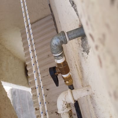 צינור מתכת עם ברז פלסטיק על קיר