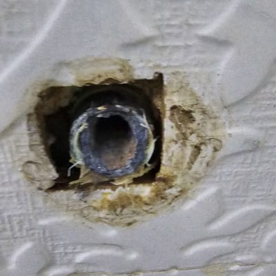 צינור מתכת חשוף בקיר עם טיח מתקלף