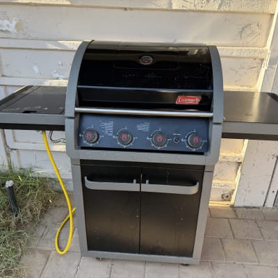 גריל גז קולמן מחובר לצינור גז צהוב בחצר