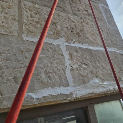 חבלים אדומים ליד קיר אבן עם חומר איטום לבן